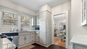 A modern kitchen with white cabinetry, a dishwasher, a microwave, and a refrigerator.