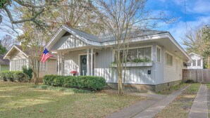 A single-story house with a front porch, a flag, and a small garden.
