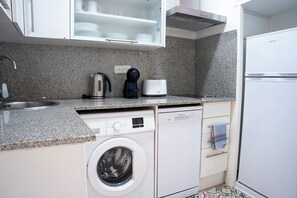 Une cuisine compacte équipée d’un lave-linge, d’une machine à café et d’un grille-pain.