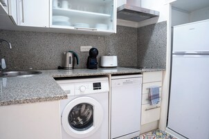 Una cucina compatta con lavatrice, macchina del caffè e tostapane.