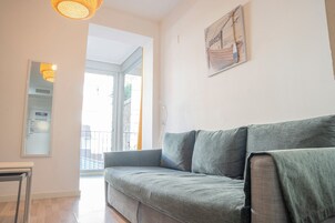 Una sala de estar moderna con un sofá gris, una mesita y una obra de arte colgada en la pared que representa una escena de playa.