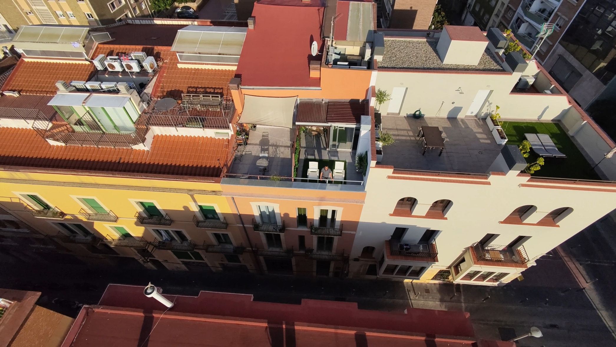 Ein mehrstöckiges Gebäude mit Balkonen, einer Dachterrasse und einem Schwimmbad.