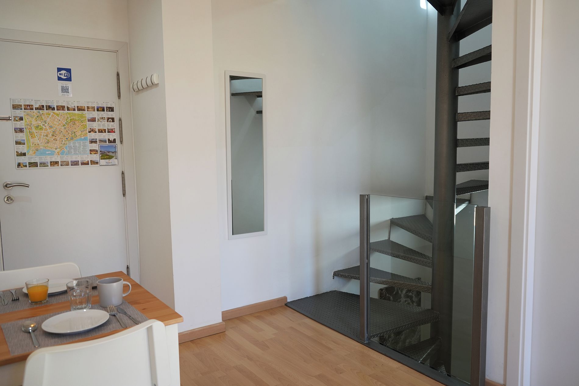 Une chambre d’hôtel avec un coin repas, une carte accrochée au mur, un miroir et un escalier.
