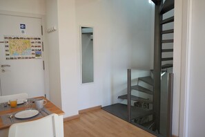 Une chambre d’hôtel avec un coin repas, une carte accrochée au mur, un miroir et un escalier.