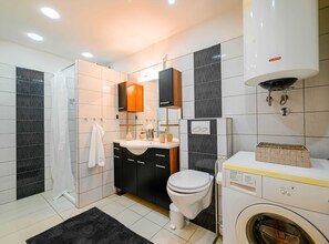 A modern bathroom with a toilet, sink, and washing machine. - Classic and Smart Rovinj Apartment With Terrace (Rovinj)