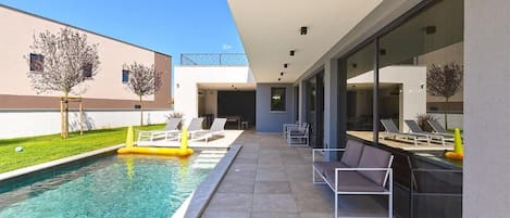 A modern outdoor pool area with lounge chairs and a dining area.