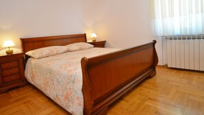 Una camera da letto con un letto di legno, due comodini con lampade, un termosifone e un soffitto in legno.