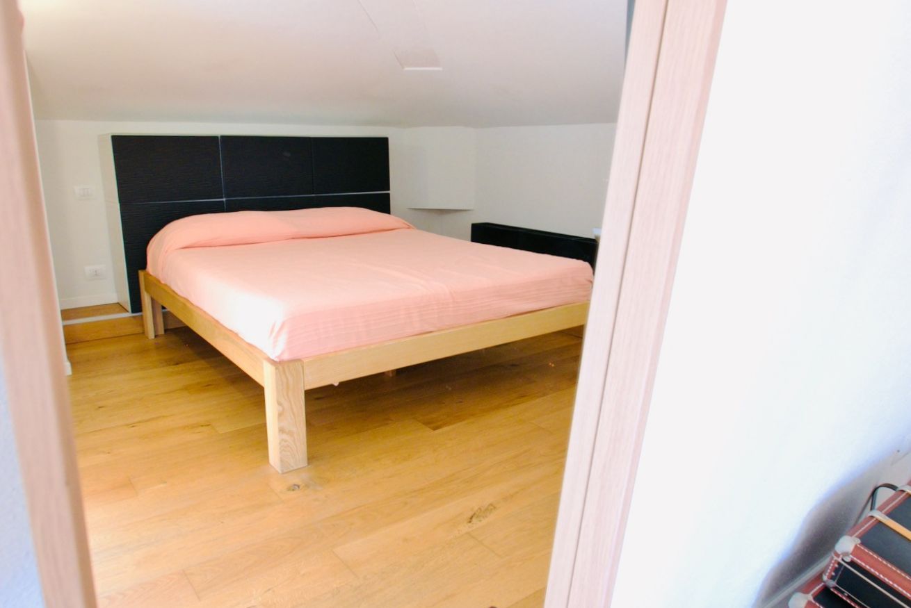 A bedroom with a wooden bed, a headboard, and a wooden floor.