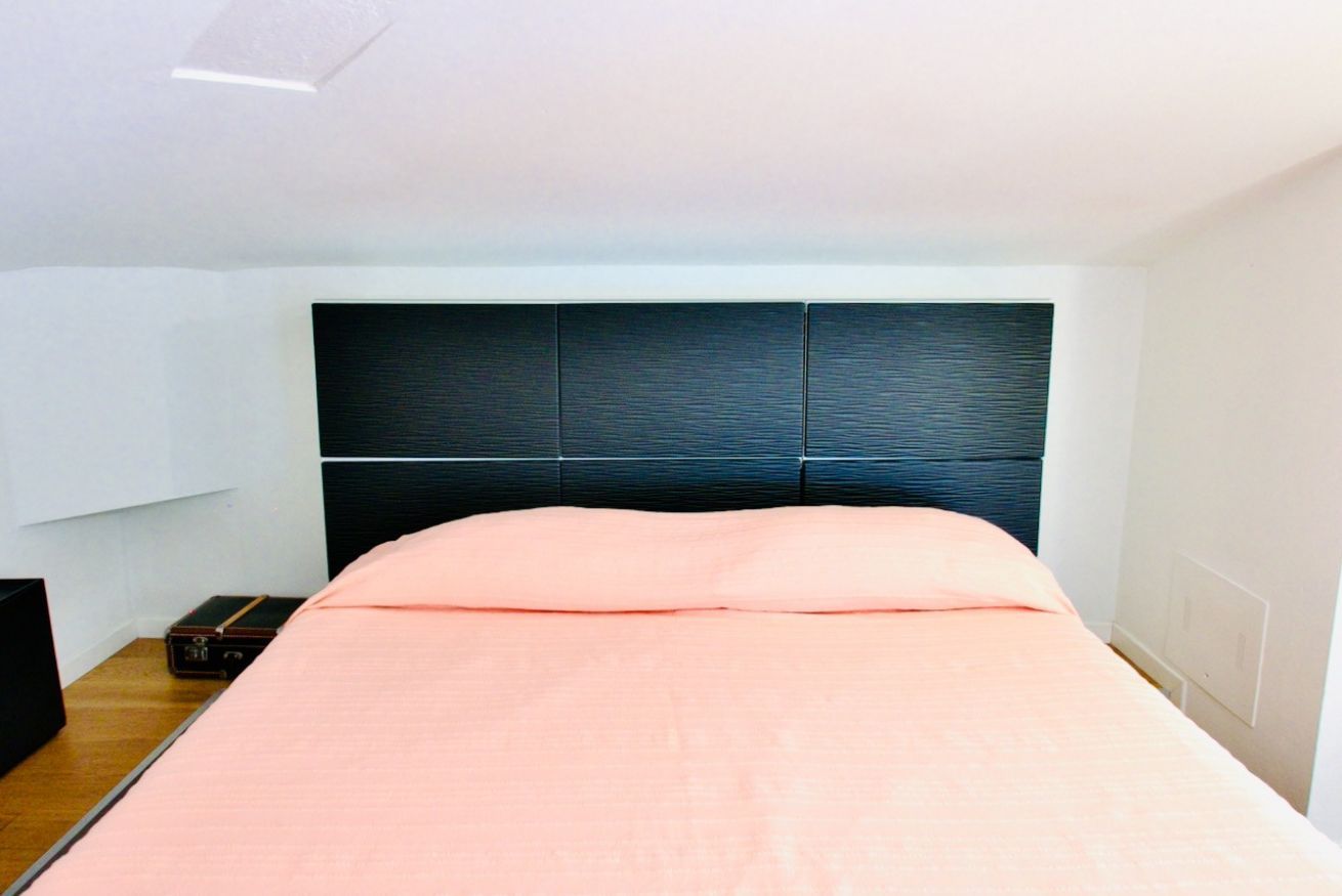 Un lit avec une tête de lit, une table de chevet et une valise.