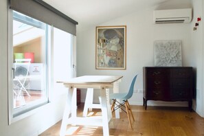 Une pièce comprenant une table et une chaise, un meuble en bois et une grande fenêtre.