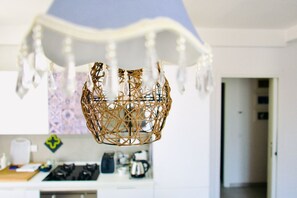 A kitchen with a hanging decorative item, a stove, and a coffee maker.
