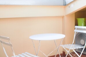 A white metal table and chairs in a corner with a green bucket and a white fan in the background. - Casa Macri, apartment in Santa Maria Novella (Firenze)