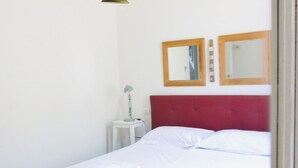 A single bed with white linens, a red headboard, and two wall-mounted mirrors. - Casa Macri, apartment in Santa Maria Novella (Firenze)