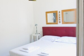 A single bed with white linens, a red headboard, and two wall-mounted mirrors. - Casa Macri, apartment in Santa Maria Novella (Firenze)