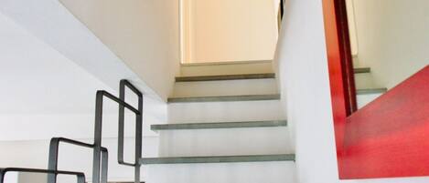Una escalera con barandilla y una puerta al final.