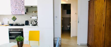 A modern kitchen with white cabinets, a dining table with chairs, and a wooden cabinet.
