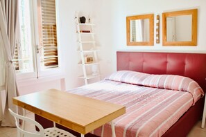 A bedroom with a bed, a wooden table, a white chair, a ladder, and two mirrors on the wall. - Casa Macri, apartment in Santa Maria Novella (Firenze)