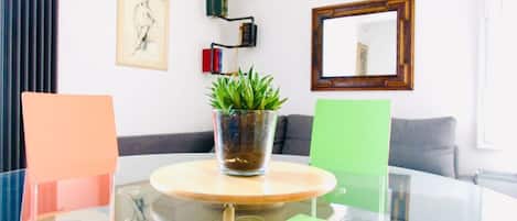 Una sala de estar moderna con una mesa de vidrio, una planta en maceta, un sofá y una estantería de pared.