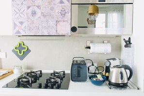 A kitchen with a gas stove, toaster, kettle, and a bowl on the counter. - Casa Macri, apartment in Santa Maria Novella (Firenze)