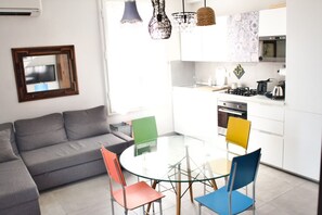 A modern living space with a sofa, a glass table, and colorful chairs. - Casa Macri, apartment in Santa Maria Novella (Firenze)