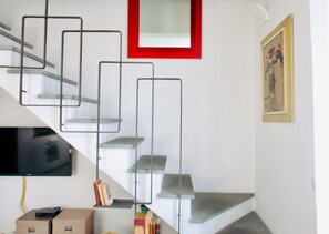 A modern staircase with glass steps and metal railings, a mounted television, and a framed artwork on the wall. - Casa Macri, apartment in Santa Maria Novella (Firenze)
