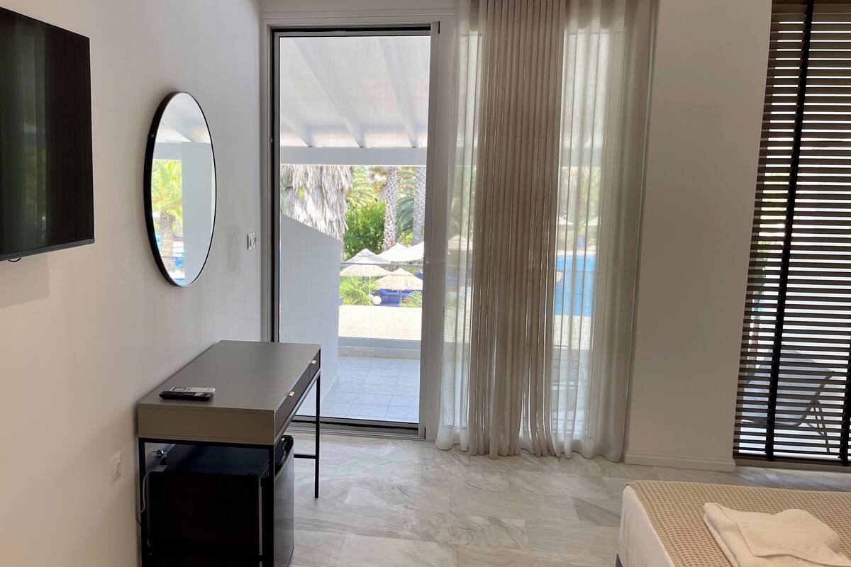 Une chambre d’hôtel moderne dotée d’un grand miroir, d’un téléviseur à écran plat, d’un bureau et d’un lit.