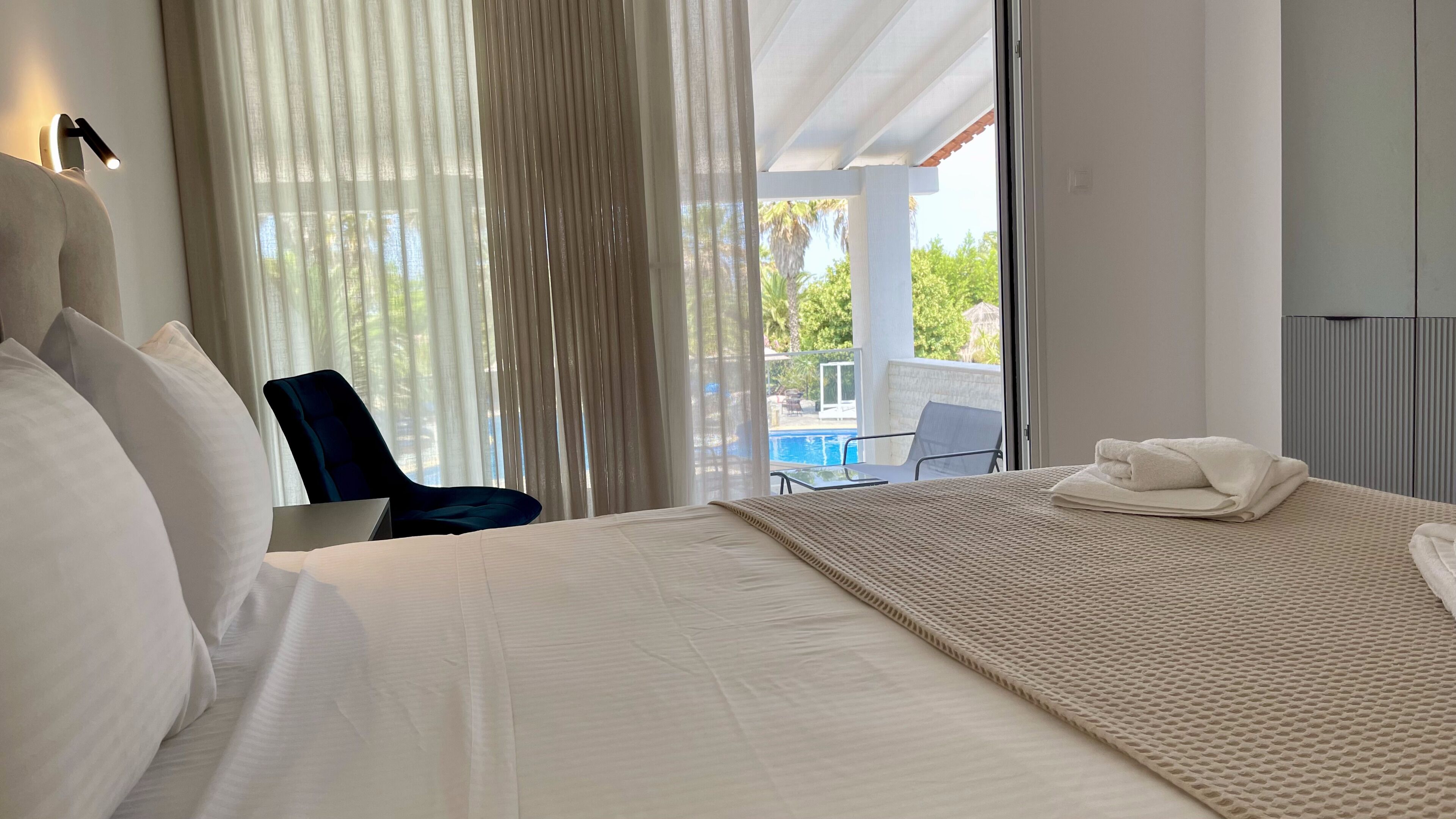 Habitación de hotel con una cama grande, una silla y vista a una piscina.