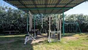 Un gimnasio al aire libre con equipo de ejercicio, una zona cubierta y un columpio.