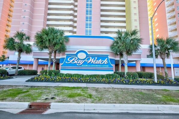 Un letrero de hotel con el nombre 'Bay Watch' y una palmera al frente.