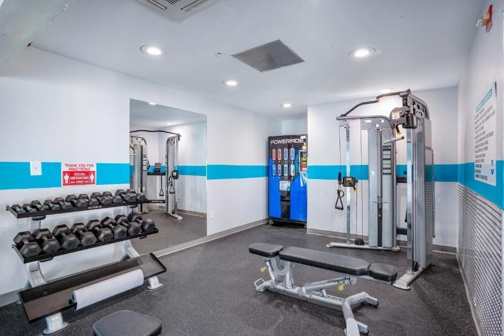 A gym with weightlifting equipment, benches, and a Powerade refrigerator.