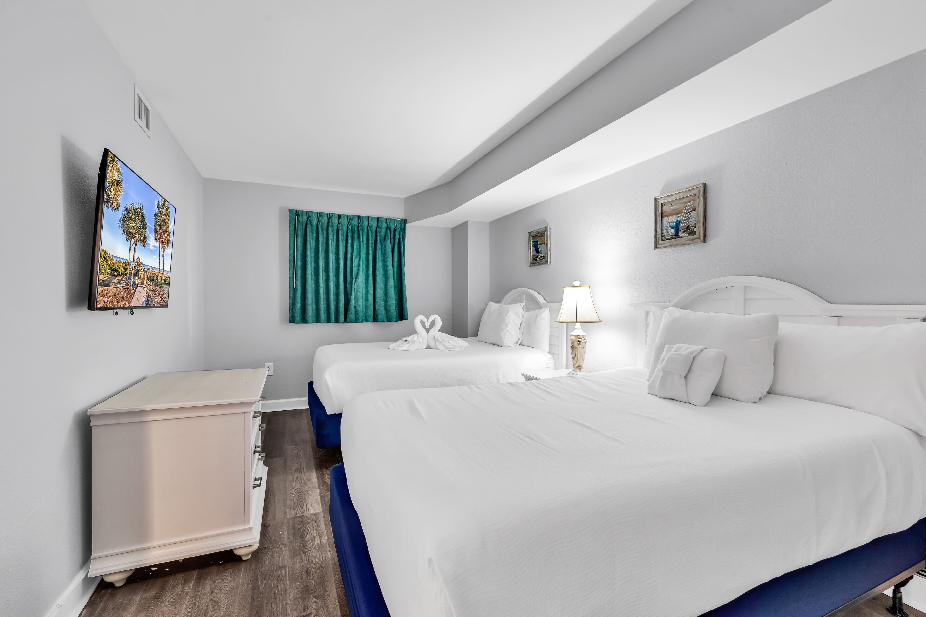Une chambre d’hôtel avec deux lits, un bureau et un téléviseur fixé au mur.