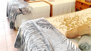 Un dormitorio con dos camas, un armario de madera y una mesita de noche con lámpara.