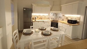A compact kitchen with white cabinetry, a built-in oven, a microwave, and a dining table set for four.