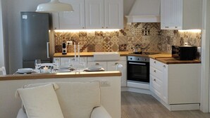 A modern kitchen with white cabinets, a wooden countertop, and patterned backsplash tiles.