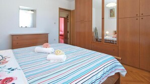 Een slaapkamer met een bed, een houten kledingkast en een spiegel.