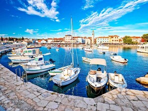 A marina with various boats docked, a stone quay, and buildings in the background. - Bright Apartment With Garden and Balcony (Vodnjan)