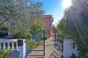 A paved pathway leading to a building with a red facade and a tiled roof. - Bright Apartment With Garden and Balcony (Vodnjan)
