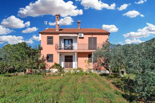 A two-story house with a balcony, surrounded by olive trees and a garden. - Bright Apartment With Garden and Balcony (Vodnjan)