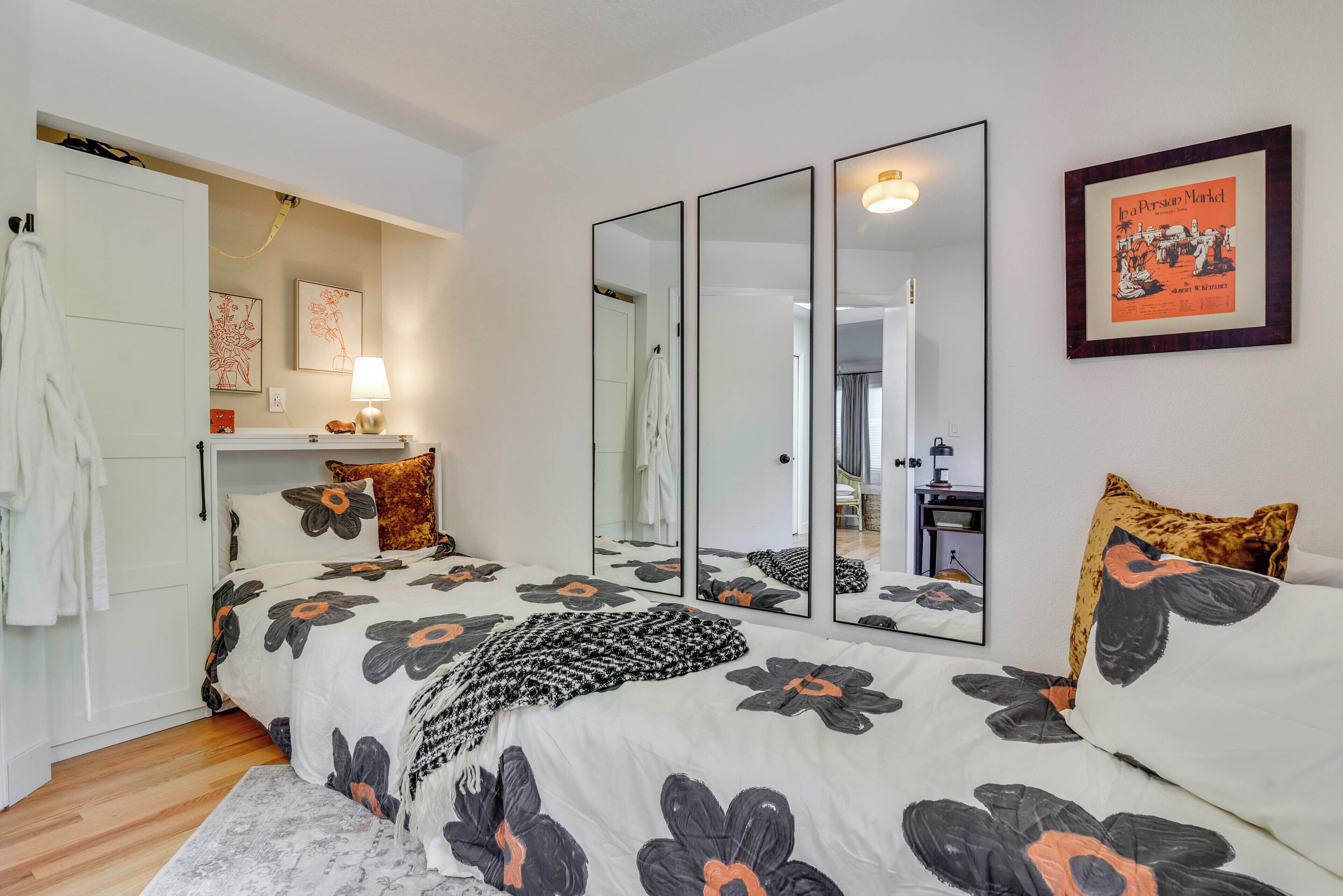 A bedroom with a large bed, a mirror, a framed picture, and a white door.