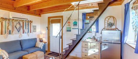 A cozy living room with a blue sofa, wooden coffee table, and a staircase leading to a kitchen area.