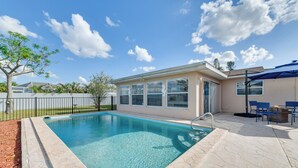 A swimming pool with a tiled deck, a covered patio area with chairs, and a fenced yard. - Family Friendly! Games! Waterfront North Port Home (North Port)