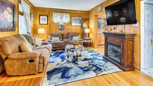 A cozy living room with a wooden floor, a large sofa, a coffee table, and a fireplace. - 1 Mi to Dtwn: Colorful Binghamton Home (Binghamton)