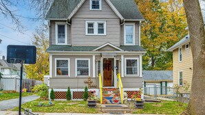 A two-story house with a front porch, a basketball hoop, and a small garden with potted plants. - 1 Mi to Dtwn: Colorful Binghamton Home (Binghamton)
