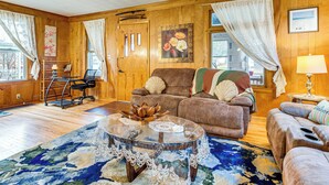 A cozy living room with wooden walls, a brown leather sofa, a glass coffee table, and a patterned rug. - 1 Mi to Dtwn: Colorful Binghamton Home (Binghamton)