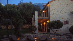 Ein Steinhaus mit Pool, Sitzgelegenheiten im Freien und einem überdachten Bereich mit Beleuchtung.