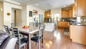 Una cocina moderna con armarios de madera, una isla central y una zona de comedor con sillas y una mesa.