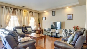 Una sala de estar con sillones de cuero, una mesa de centro de madera y un televisor de pantalla plana.