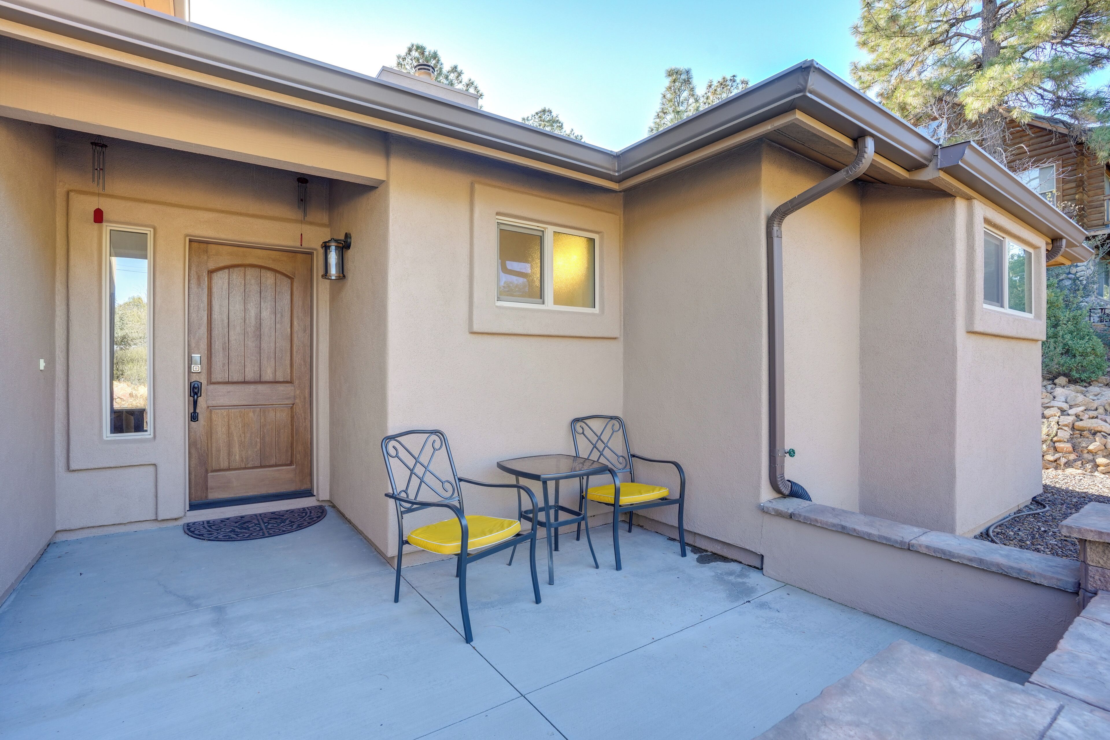 A house exterior with a front door, two chairs, and a small table.