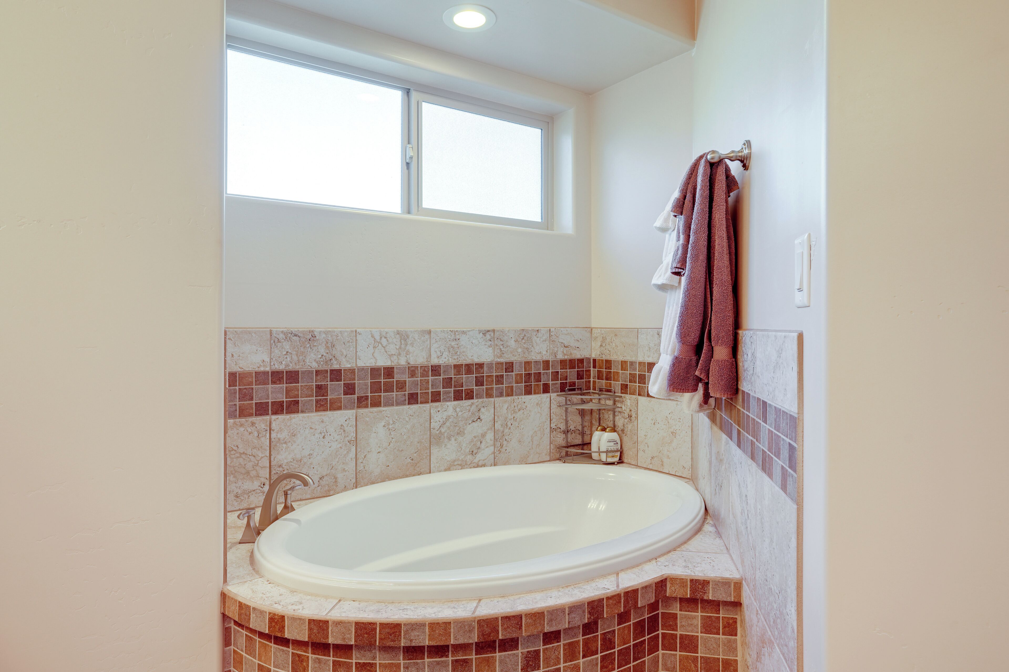 A bathroom with a freestanding bathtub, a window, and a tiled backsplash.