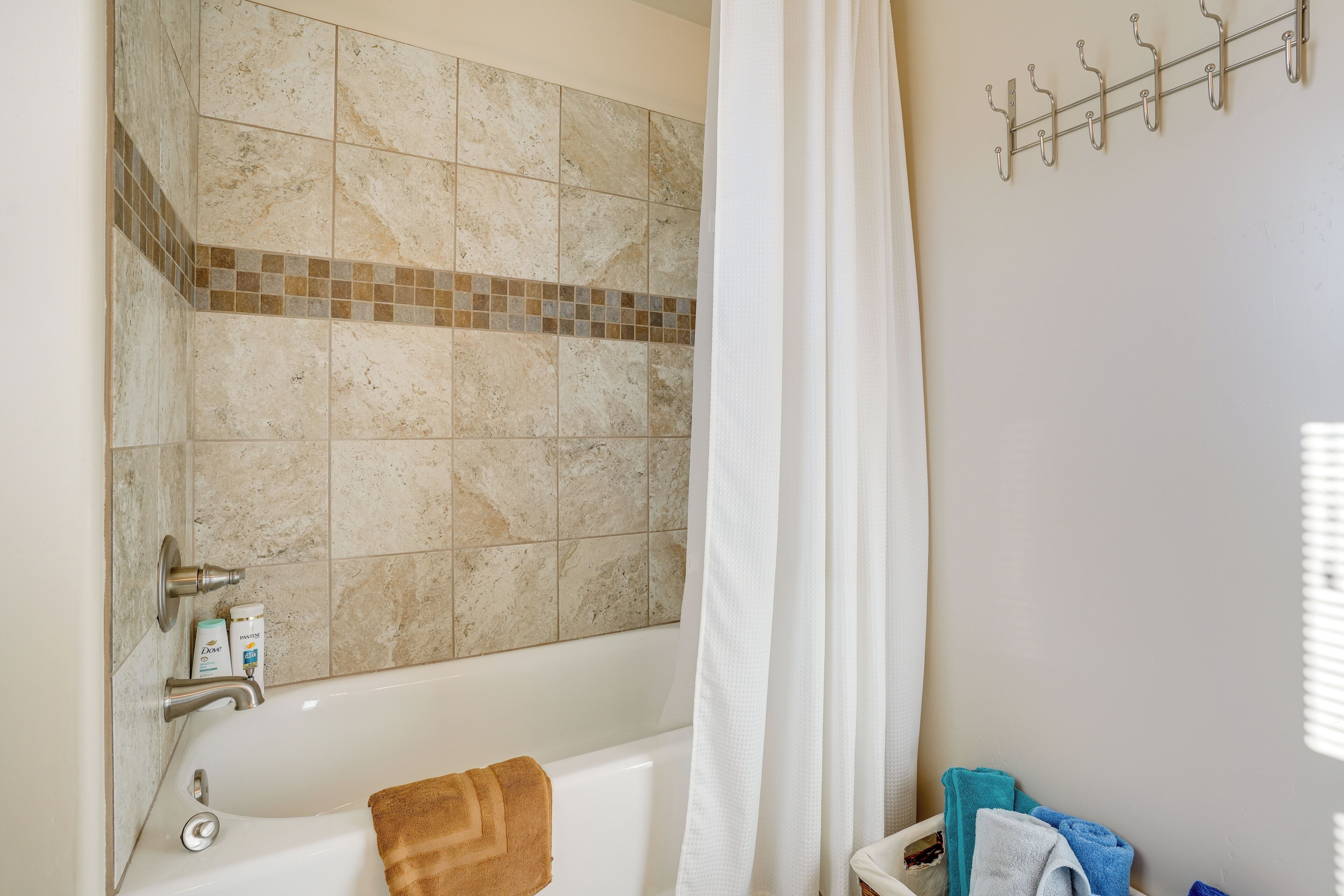 A bathroom with a bathtub, a shower curtain, a towel rack, and toiletries on the wall.